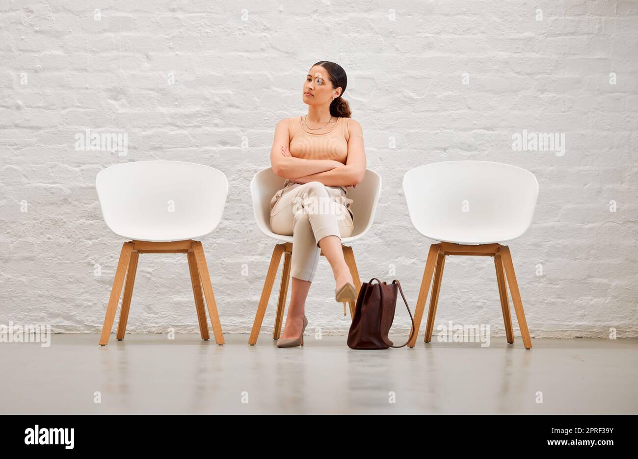 Impiego, assunzione e assunzione con una giovane donna d'affari seduta su una sedia in attesa del colloquio con le risorse umane. Candidata alla rosa femminile che sembra impaziente o nervosa per una riunione Foto Stock