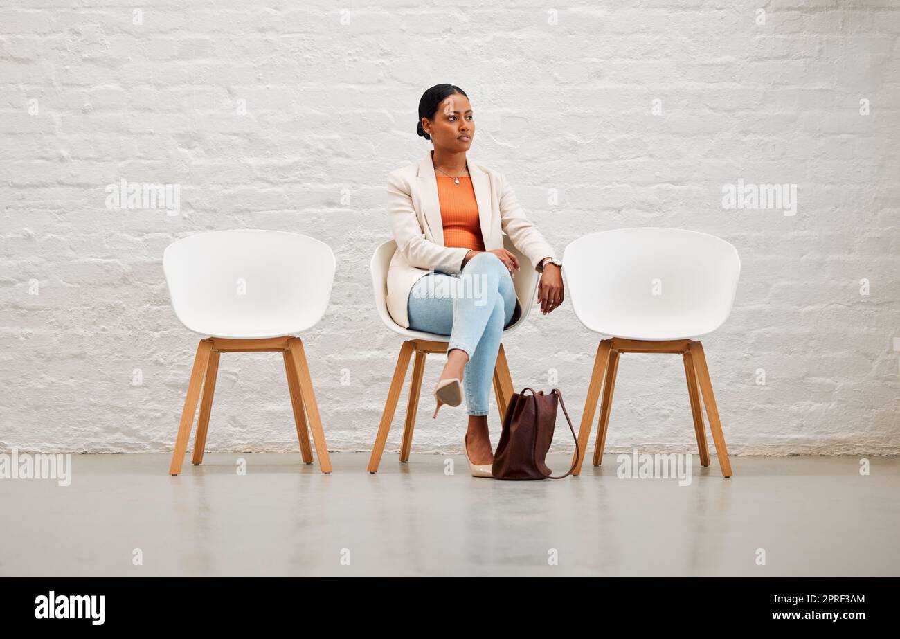 Impiego, assunzione e reclutamento con una giovane donna seduta su una sedia in attesa del colloquio con le risorse umane in un ufficio creativo. Candidata della rosa rosa femminile pronta per la sua riunione o appuntamento Foto Stock