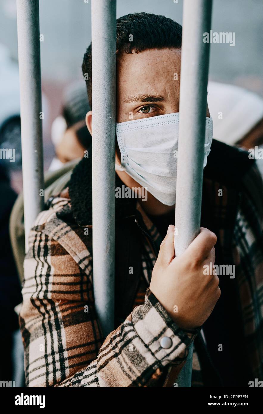 Malato, rifugiato di un giovane paziente covid in quarantena per attraversare il confine con una maschera medica. Uomo straniero in una folla di carceri durante una pandemia seguendo le norme di sicurezza sanitaria del virus. Foto Stock