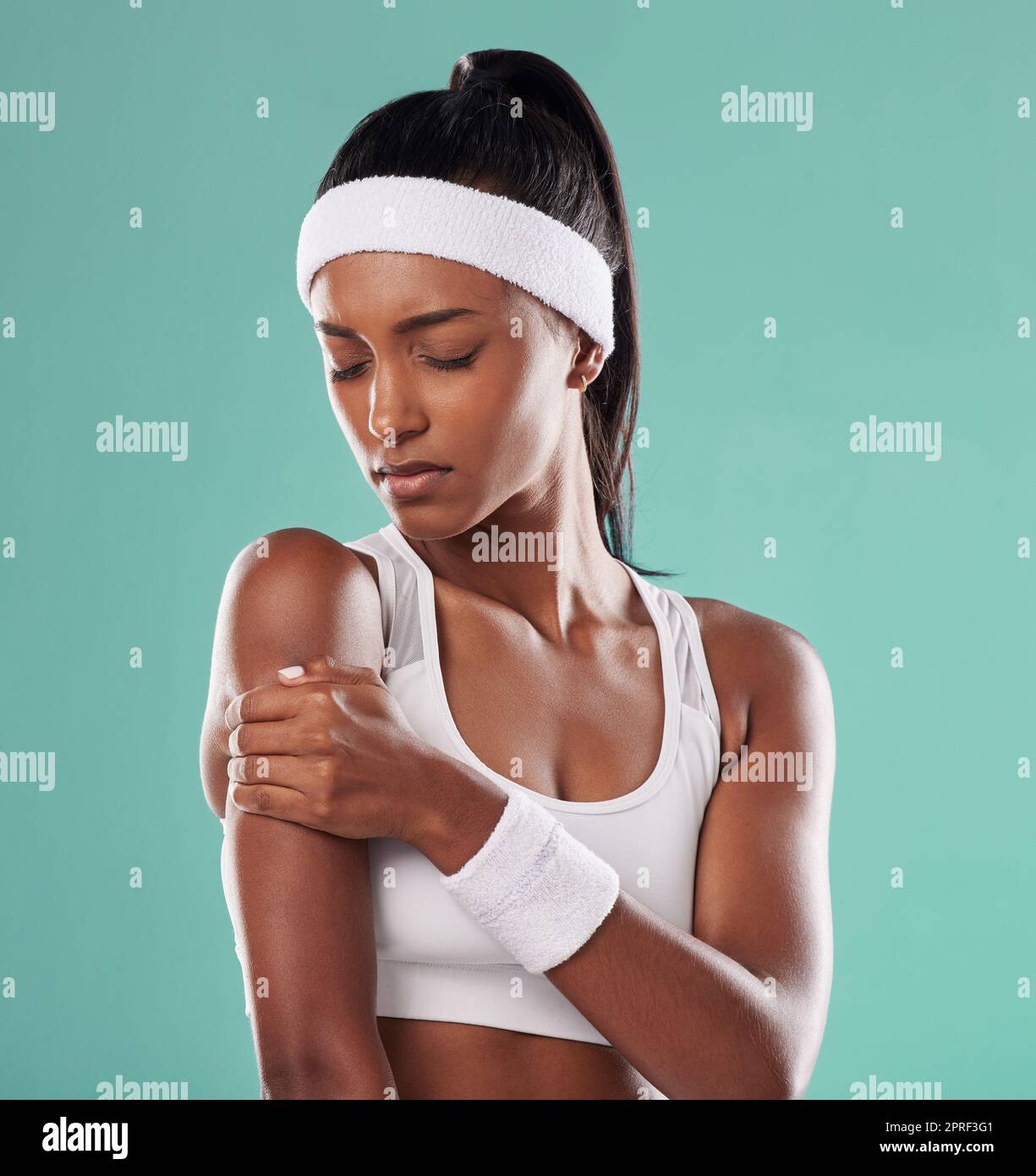 Tennista con lesioni sportive, ferite o dolori al braccio dopo l'allenamento sullo sfondo verde dello studio. Atleta professionista che soffre di tensione muscolare, incidente e infiammazione sul suo corpo Foto Stock