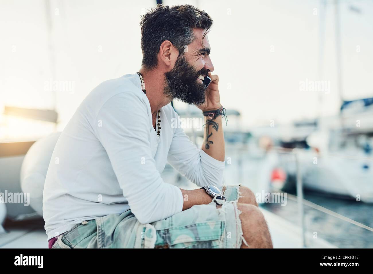 Fare una chiamata prima di partire. Un uomo che parla al telefono mentre si siede sul suo yacht. Foto Stock