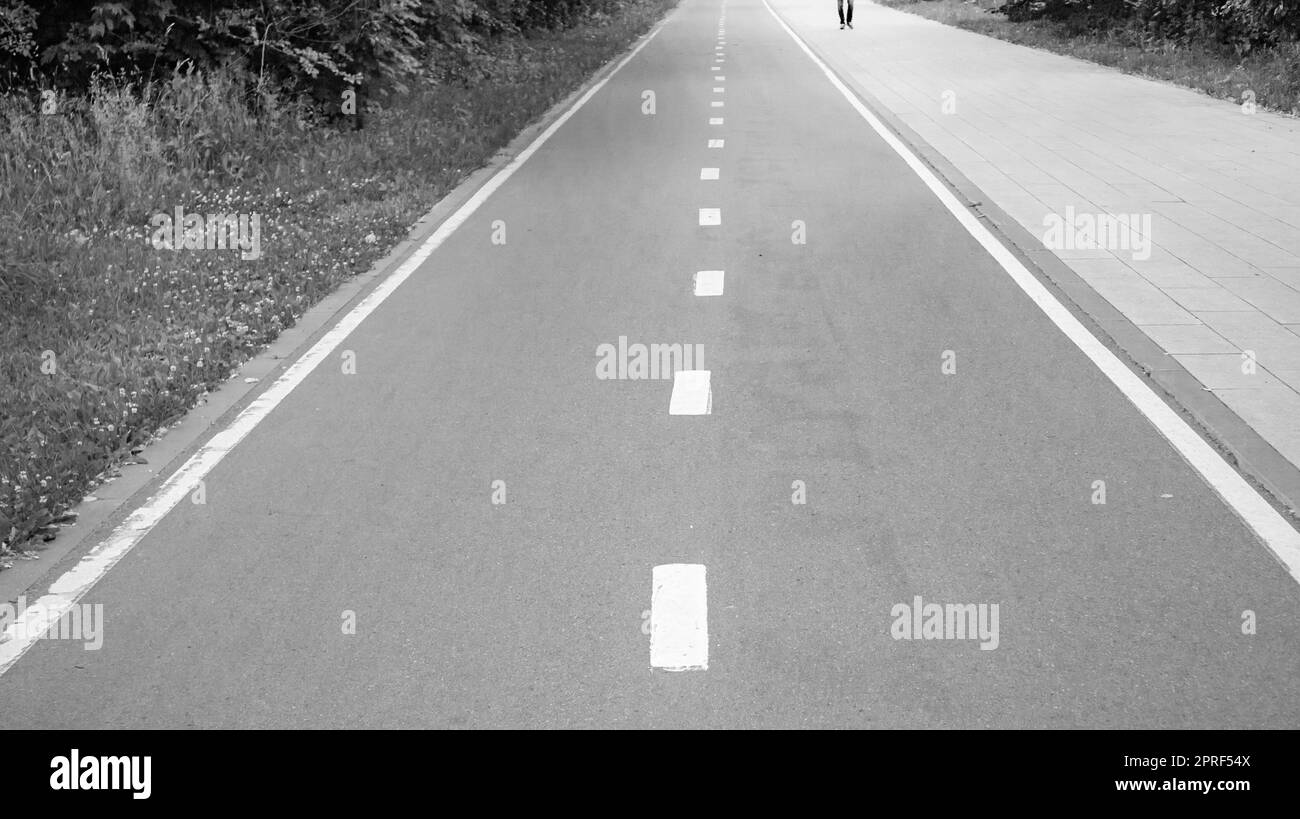 Primo piano di una strada asfaltata con una linea di demarcazione intermittente. Messa a fuoco selettiva, fotografia in bianco e nero Foto Stock