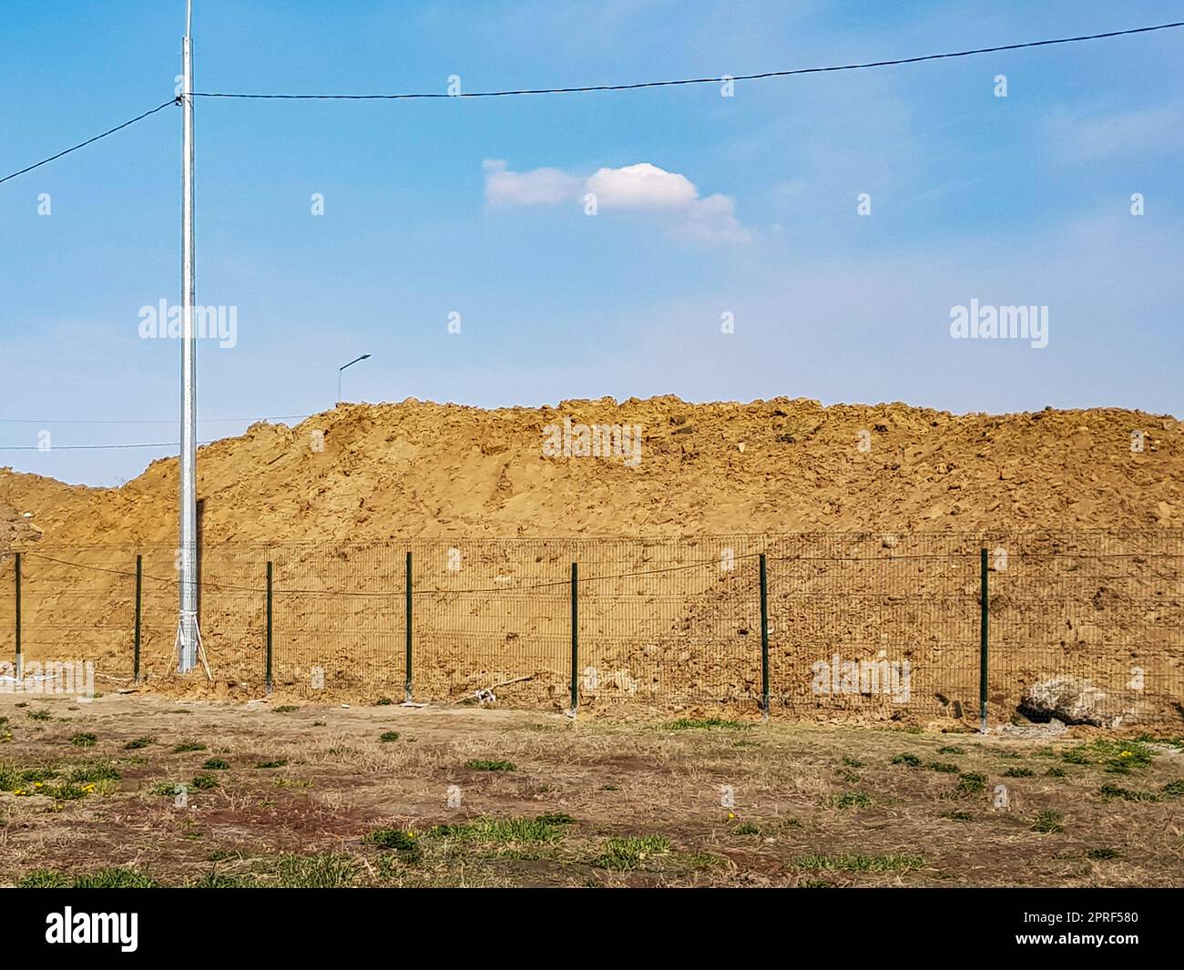 Lavori di costruzione all'aperto con un grande mucchio di sabbia dietro la recinzione e un paesaggio paradisiaco. Foto Stock