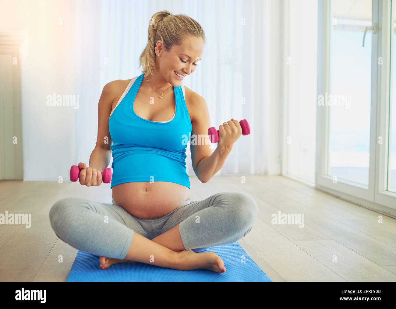Prendendosi cura di due ora. Una donna incinta che lavora fuori con i pesi nel paese. Foto Stock