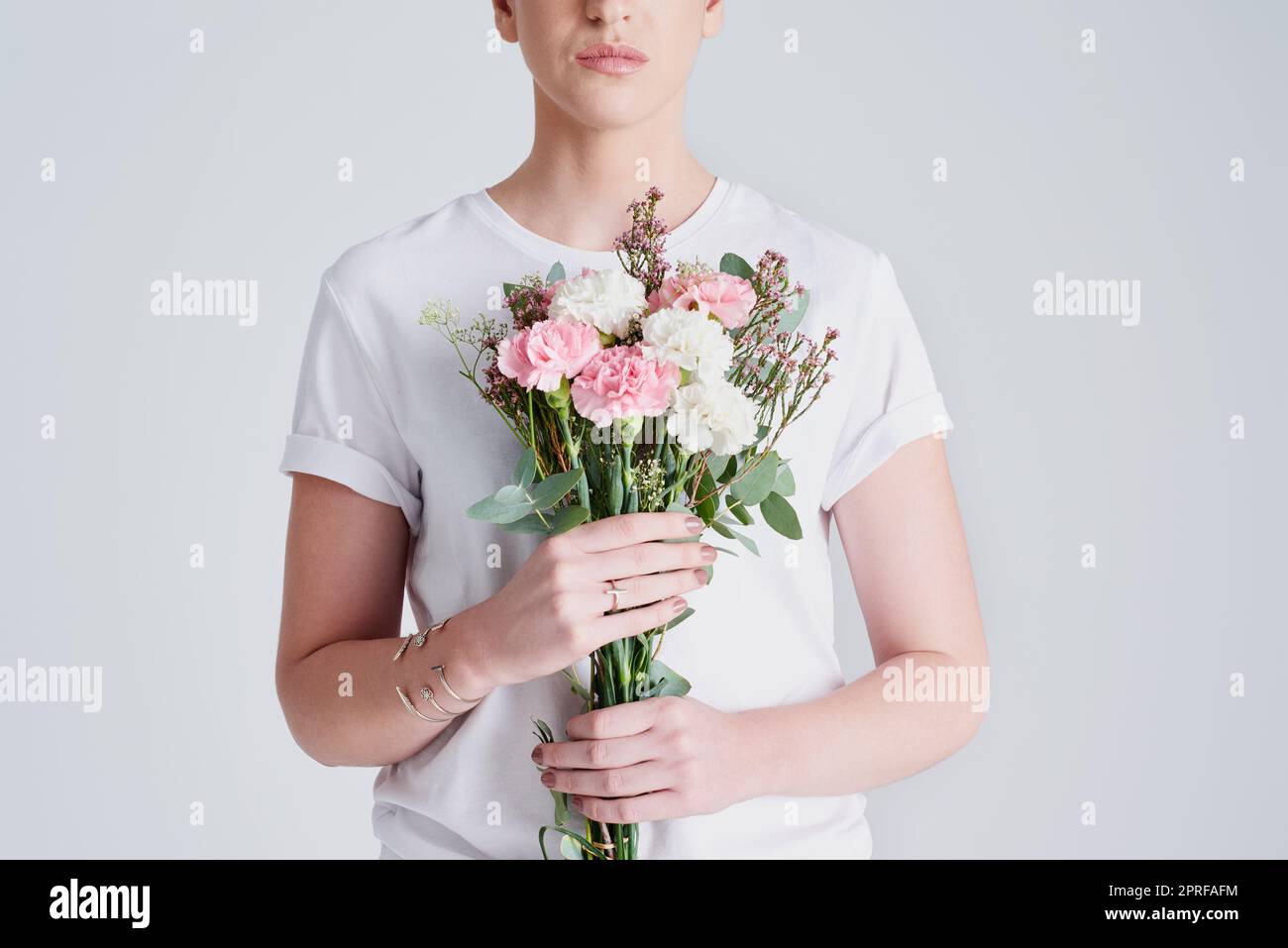 Vivere liberi come fiori in natura. Studio shot di una donna irriconoscibile che tiene un bouquet di fiori su uno sfondo grigio. Foto Stock