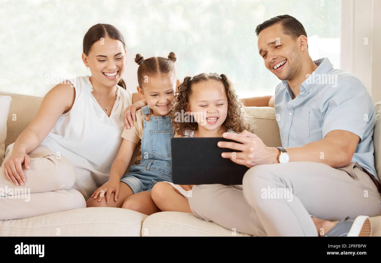 Connesso con un legame di appartenenza. una giovane famiglia che si siede insieme mentre guarda qualcosa su un tablet digitale Foto Stock
