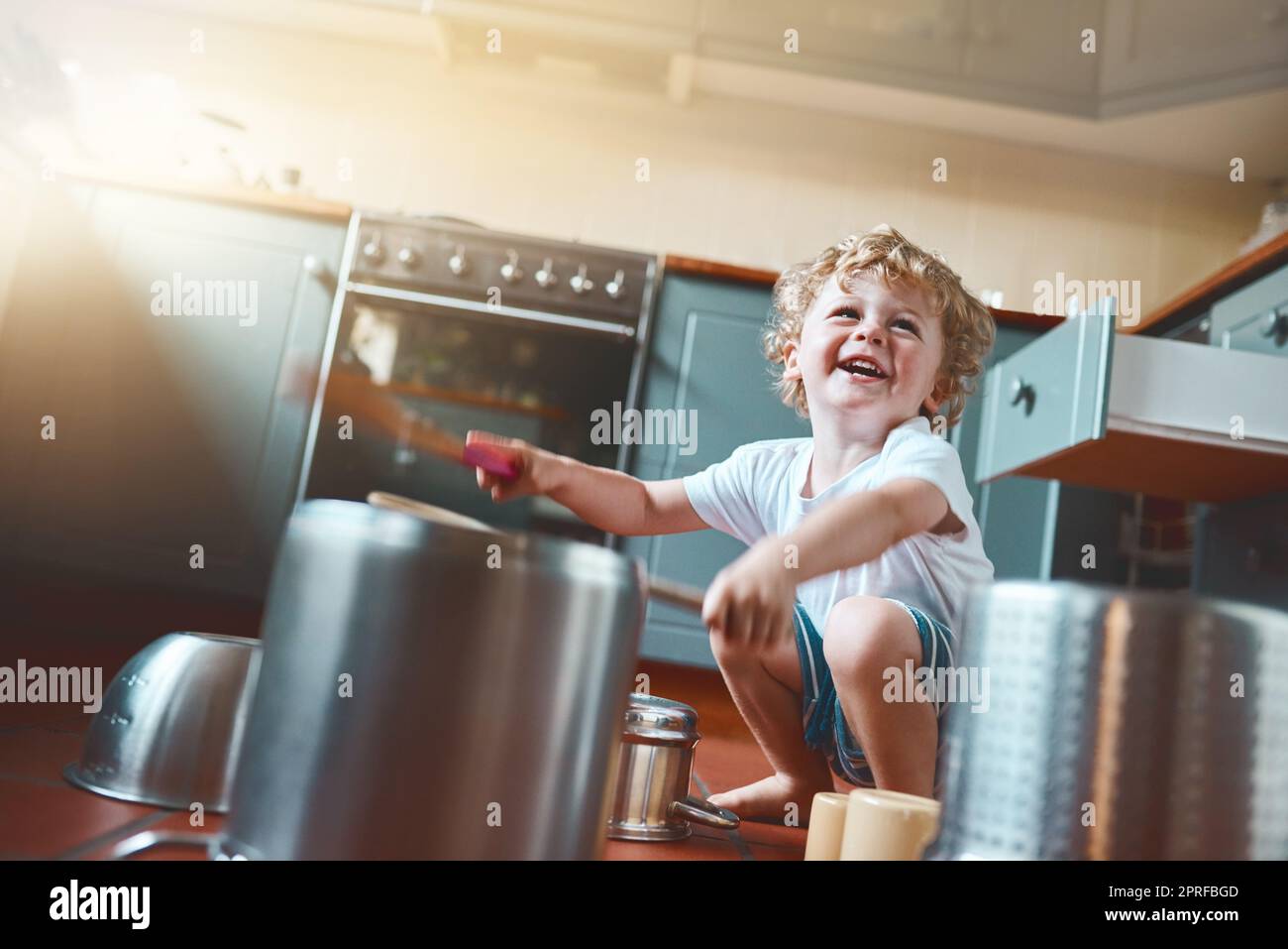 La musica in qualsiasi forma aiuta lo sviluppo di un bambino. Ritratto di un adorabile ragazzino che gioca con pentole in cucina. Foto Stock