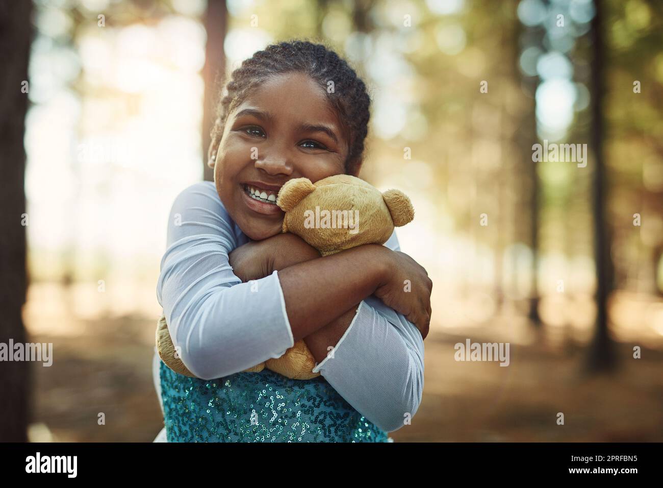 Coccole per la sua soffice amica. Ritratto di una bambina che gioca nel bosco con il suo orsacchiotto. Foto Stock