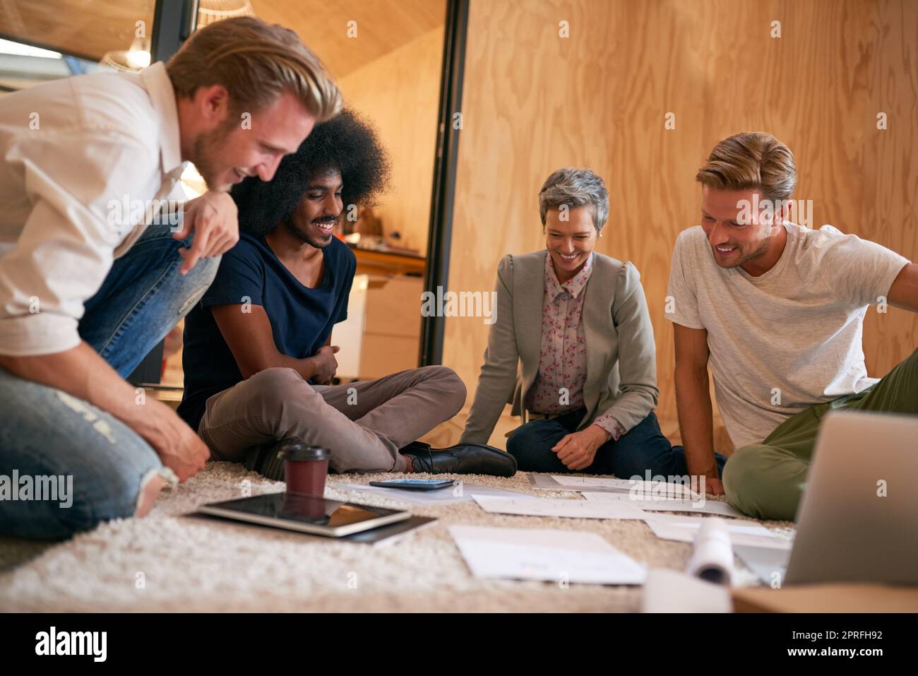 Mirando a raggiungere l'eccezionale insieme. Un team di designer di brainstorming sul pavimento in un ufficio. Foto Stock