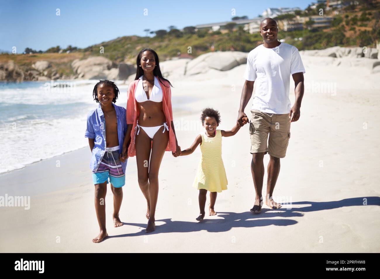 Godendo la sabbia tra le dita dei piedi. Una famiglia afro-americana che si gode una giornata in spiaggia insieme Foto Stock