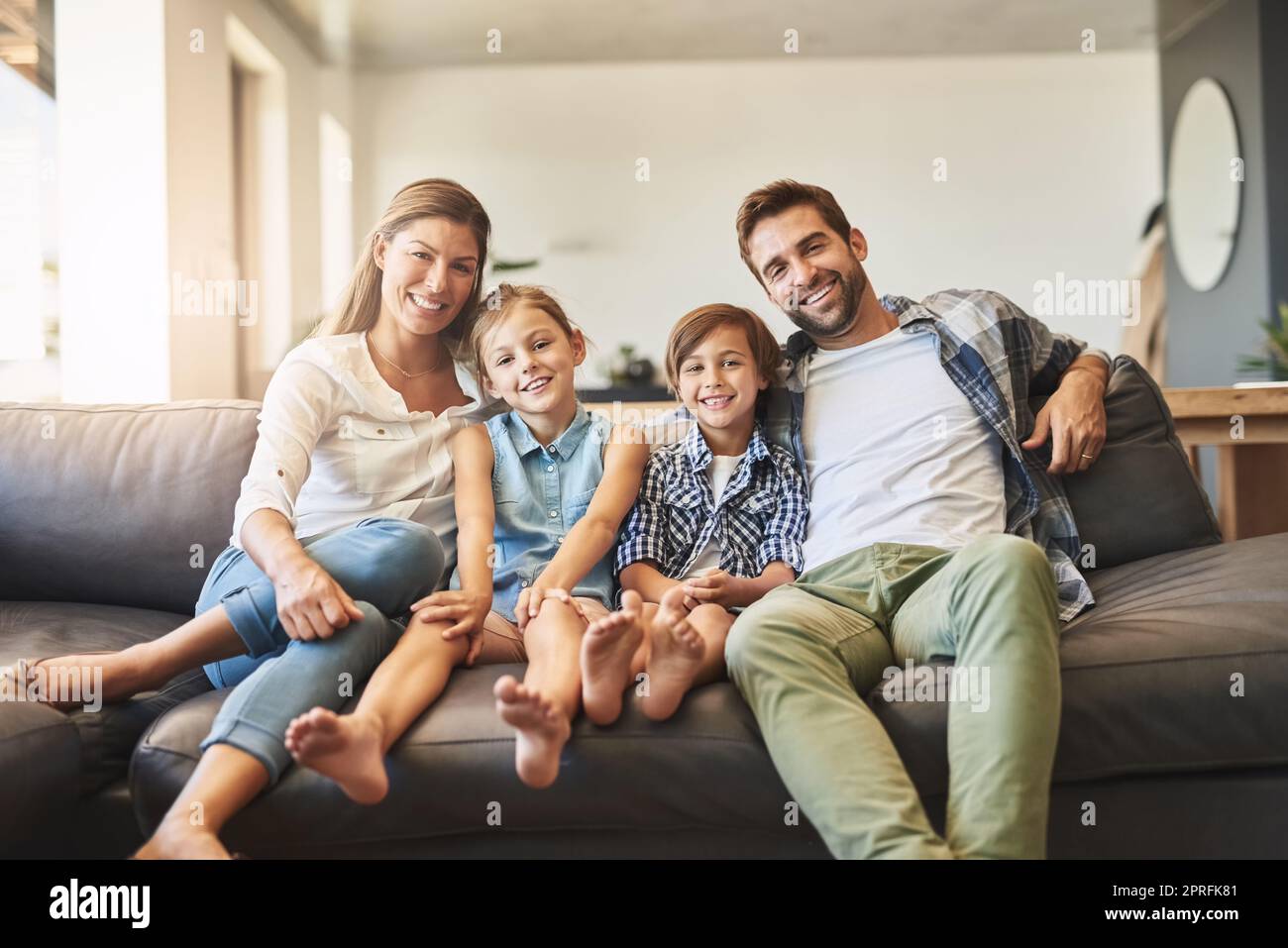 Niente dice casa come l'amore della famiglia. Una famiglia felice di quattro persone che si rilassano insieme sul divano di casa. Foto Stock