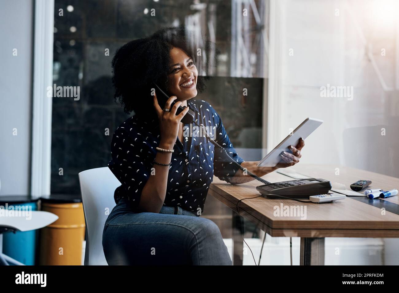Faccia sempre i follow-up sui vostri affari. Una giovane designer femminile che fa una chiamata mentre tiene un tablet digitale alla sua scrivania dell'ufficio. Foto Stock
