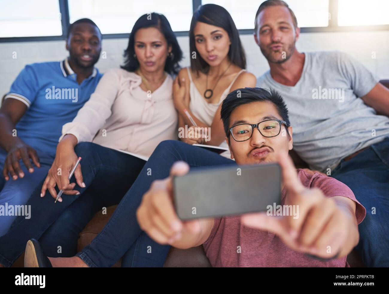Mettere i loro volti selfie. Un gruppo felice di colleghi creativi in posa per un selfie insieme in ufficio. Foto Stock