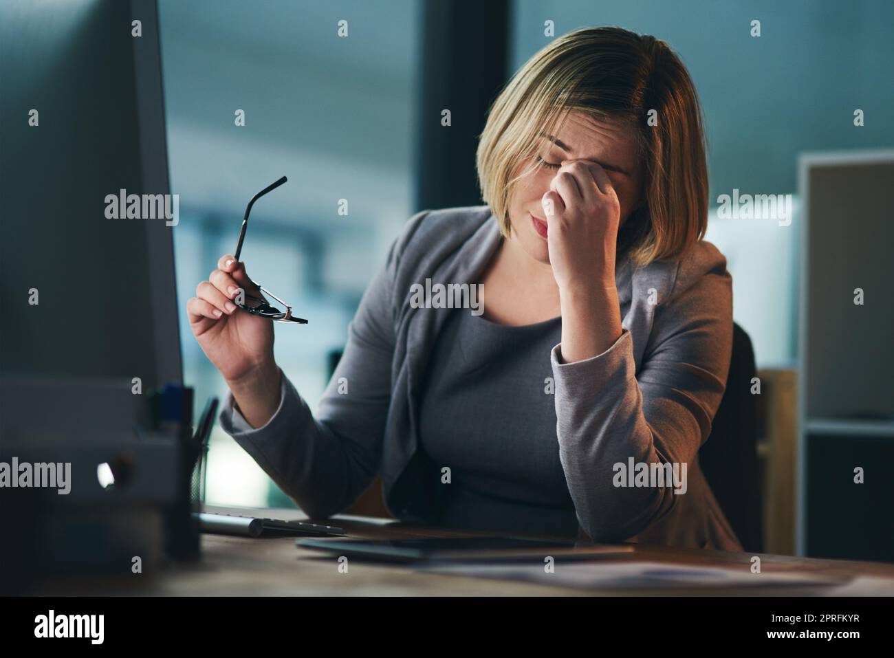 Queste ultime notti non sono un bene per lei: Una giovane donna d'affari che guarda stressato mentre lavora tardi in un ufficio. Foto Stock