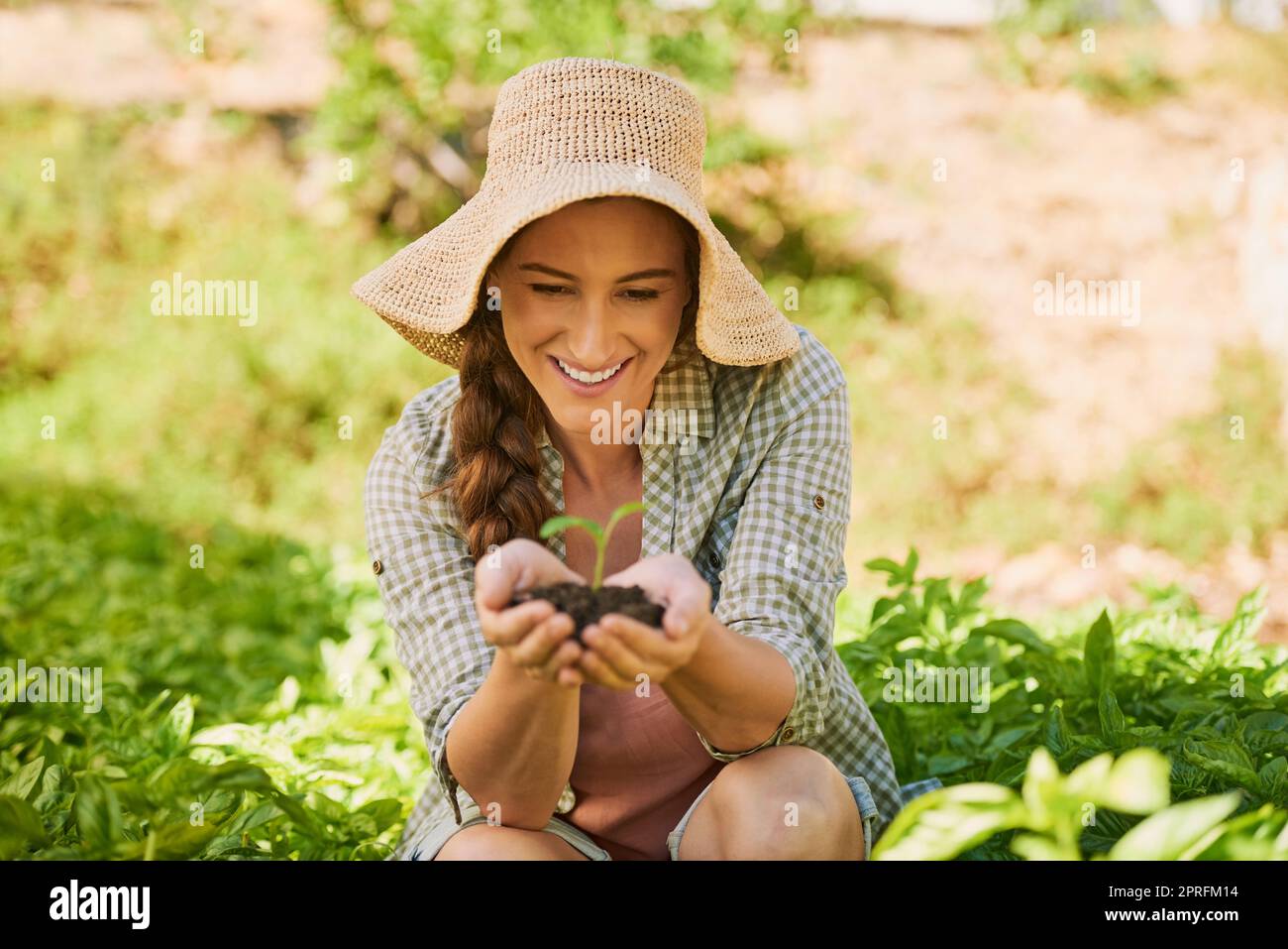 La vita non cessa mai di stupirla. Un giovane coltivatore felice che tiene un mucchio di suolo con un piantine che cresce fuori di esso. Foto Stock