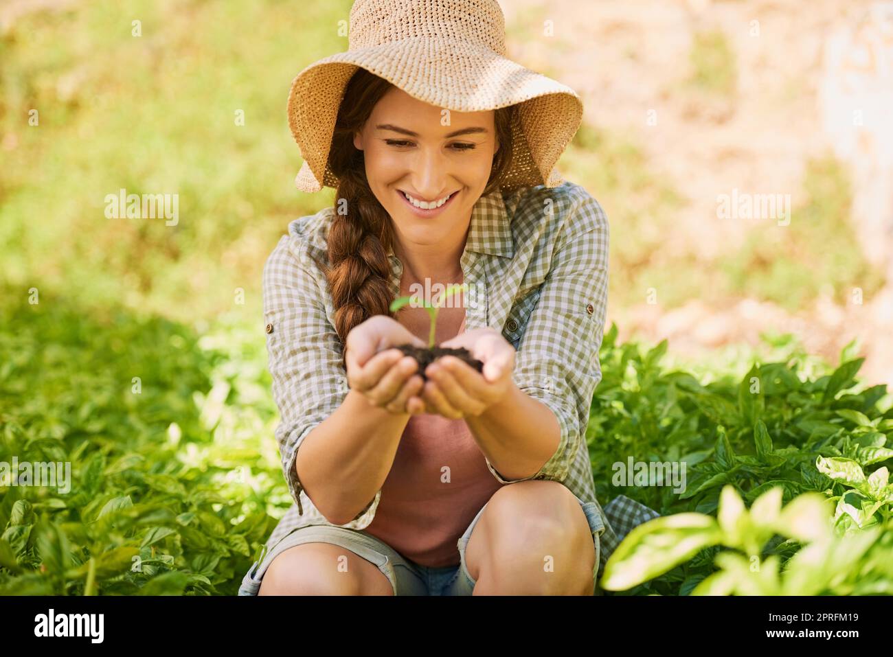 Una nuova vita è bella da vedere: Un giovane agricoltore felice che tiene un mucchio di terreno con una piantina che cresce fuori di esso. Foto Stock