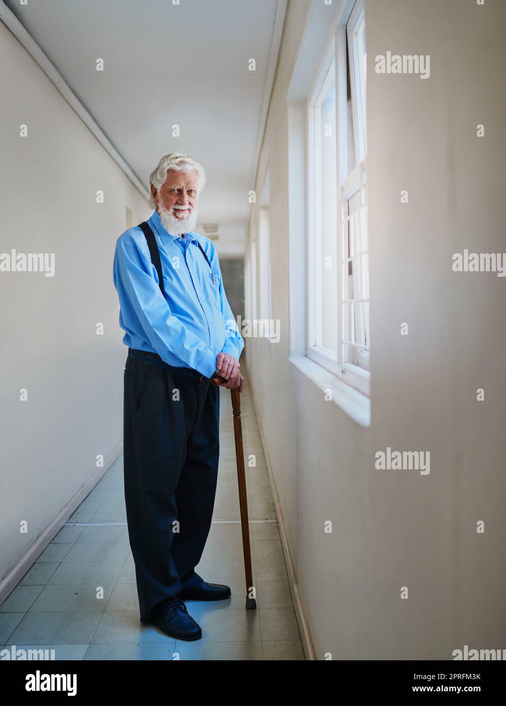 È bene essere un pensionato. Ritratto di un uomo anziano felice che si posa nel corridoio della sua casa di cura. Foto Stock