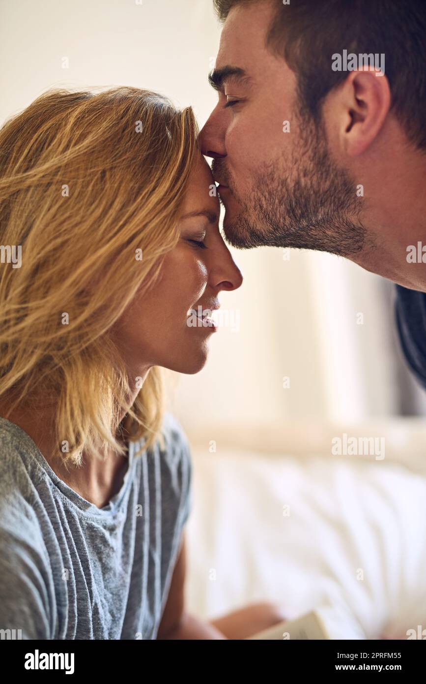 Il Buongiorno. perfetto Primo piano scatto di un bell'uomo che bacia la sua attraente ragazza sulla fronte a casa. Foto Stock