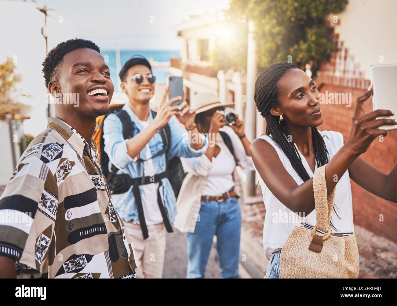 Viaggiate con persone che fanno fotografie di architettura all'estero in una strada di città straniera. Uomini e donne influencer o turisti che fanno ricordi al telefono delle vacanze estive per l'app di social media online Foto Stock