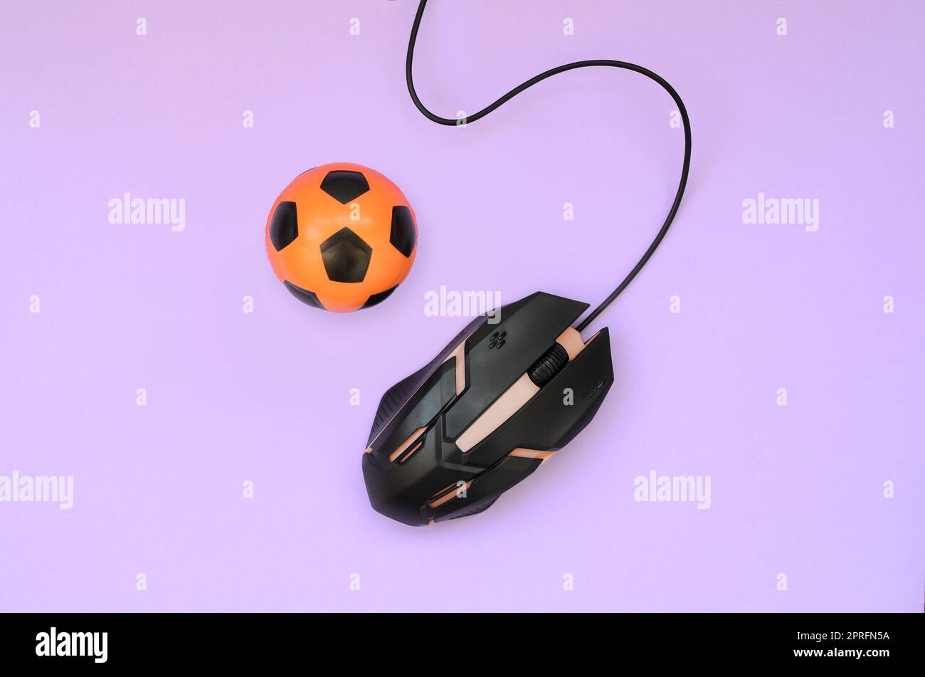 Pallone da calcio con il mouse del computer su sfondo viola. Concetto di videogiochi, eSports, sport scommesse e gioco d'azzardo online Foto Stock