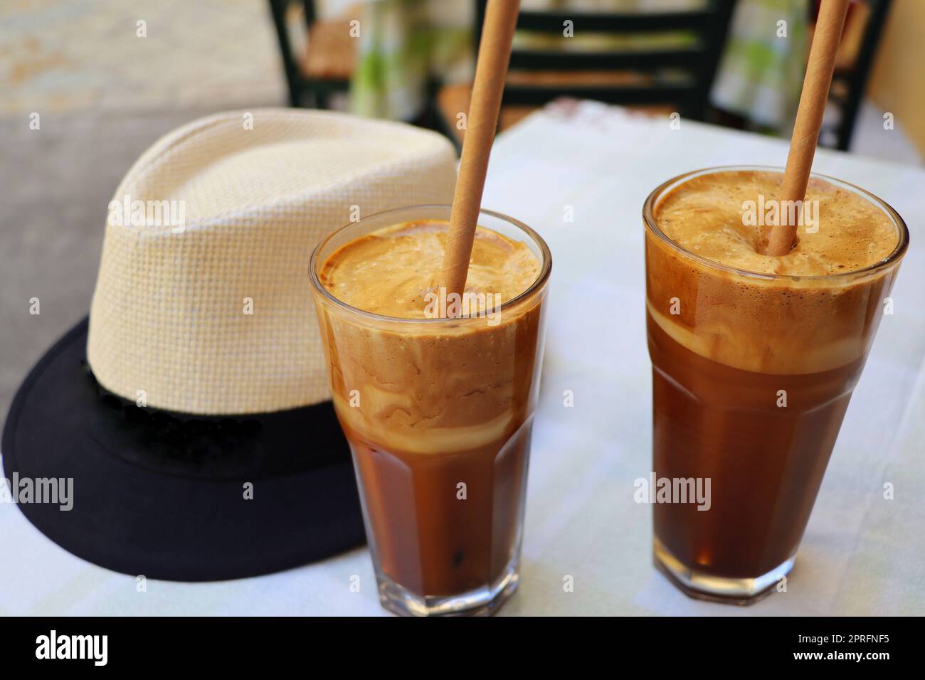 Tradizionale caffè greco freddo Frappe con schiuma di latte, caffè istantaneo e cubetti di ghiaccio in vetro alto primo piano nel caffè. Foto Stock