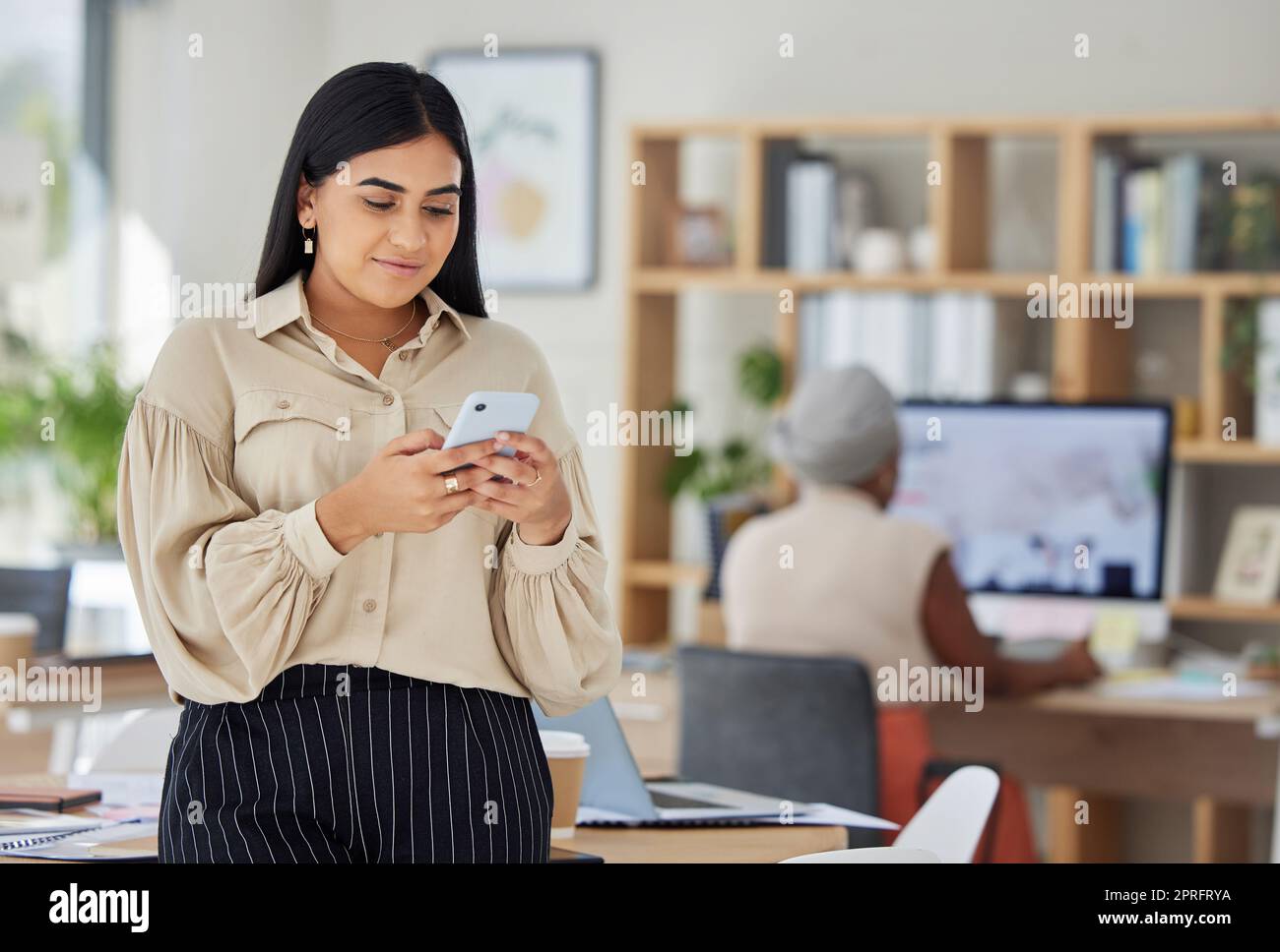 Telefono, comunicazione e networking con una donna d'affari che legge un messaggio nel suo ufficio al lavoro. Contattateci con tecnologia mobile o wifi e connettetevi al futuro con crescita e sviluppo Foto Stock