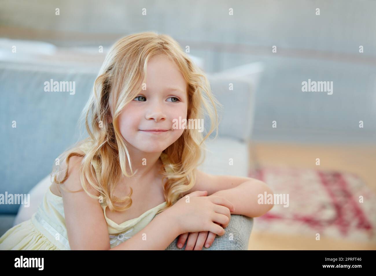 I bambini hanno menti meravigliose. Una bambina carina che guarda premurosa mentre si siede sul divano a casa. Foto Stock