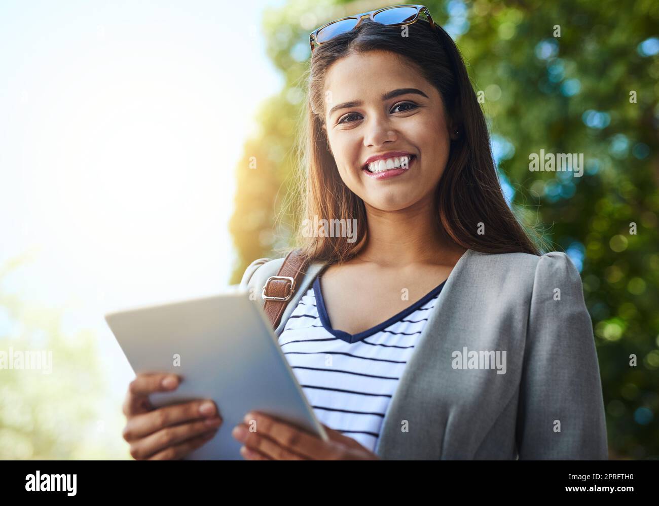 Il lavoro non si ferma mai, e nemmeno io. Ritratto ritagliato di una giovane donna attraente utilizzando il suo tablet mentre si va al lavoro. Foto Stock