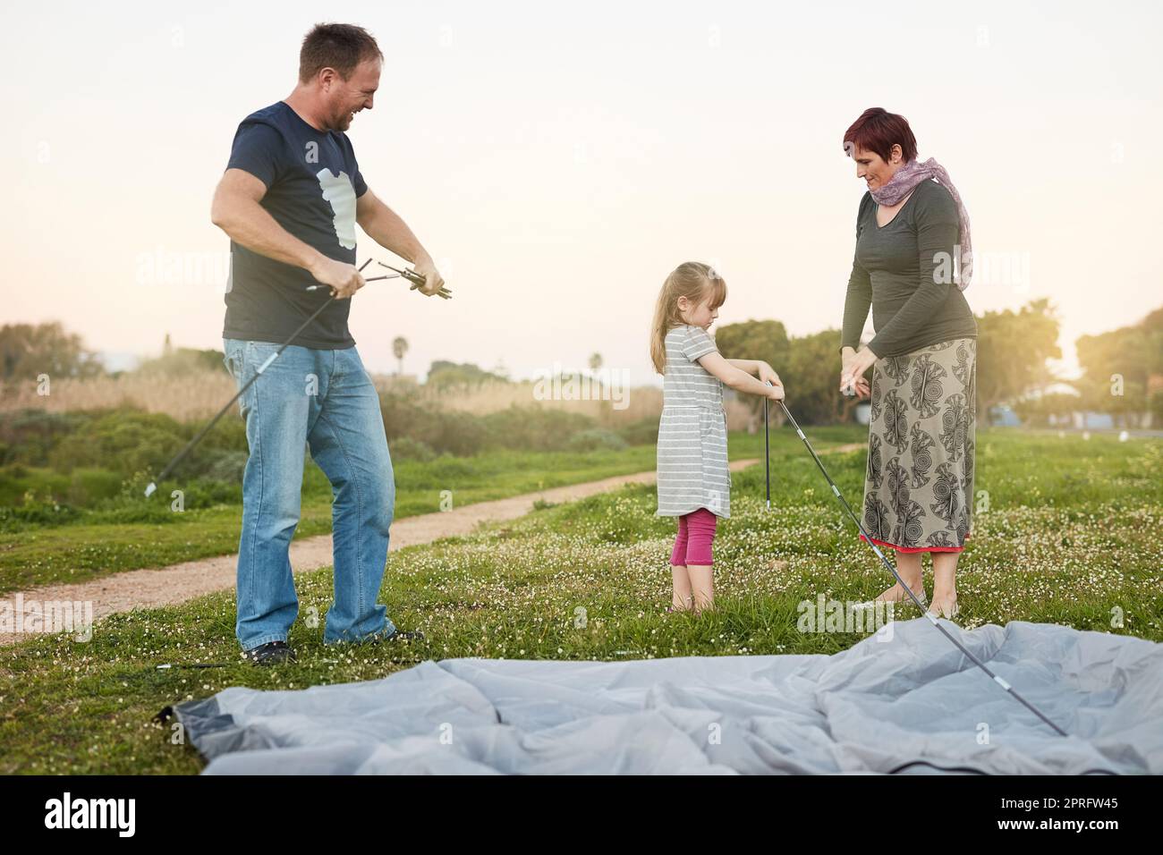 Molte mani fanno lavoro leggero, una famiglia giovane che mette insieme una tenda. Foto Stock
