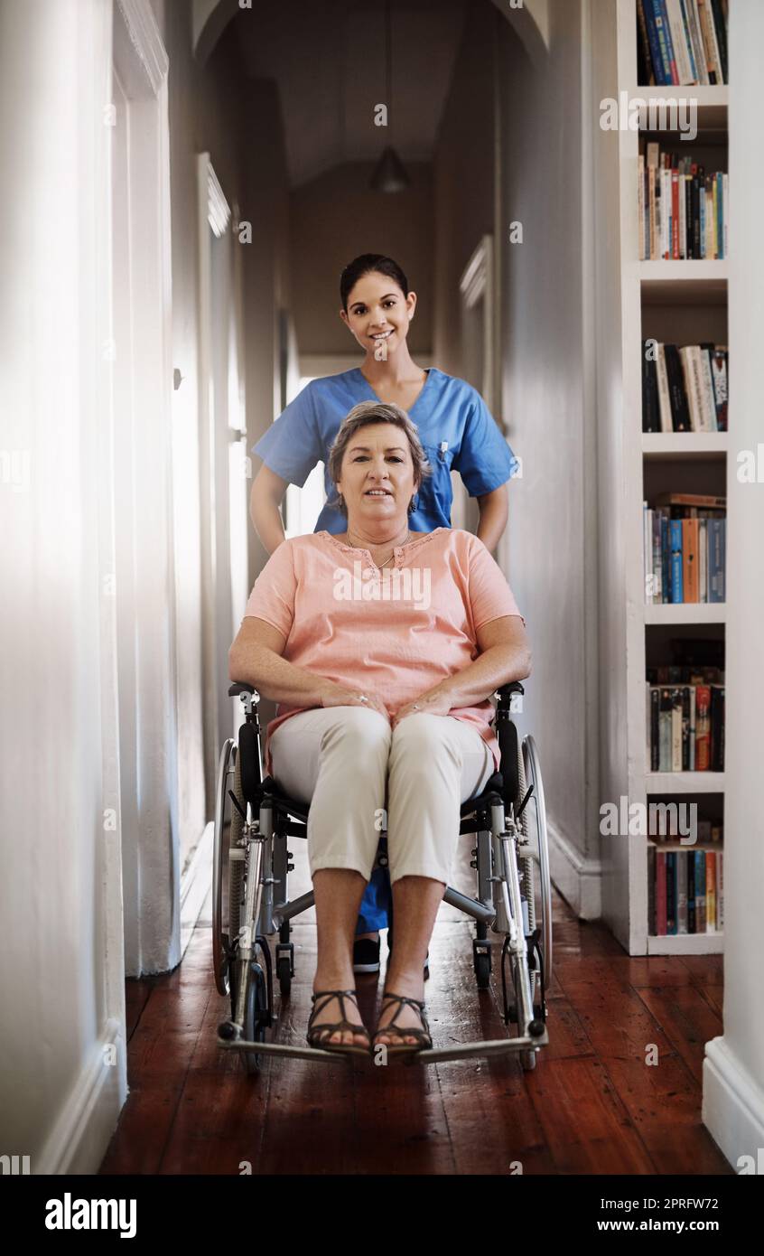 Come muoversi con un po' di supporto. Ripresa a tutta lunghezza di una giovane e attraente caregiver che spinge un paziente anziano in una sedia a rotelle in una casa di cura. Foto Stock
