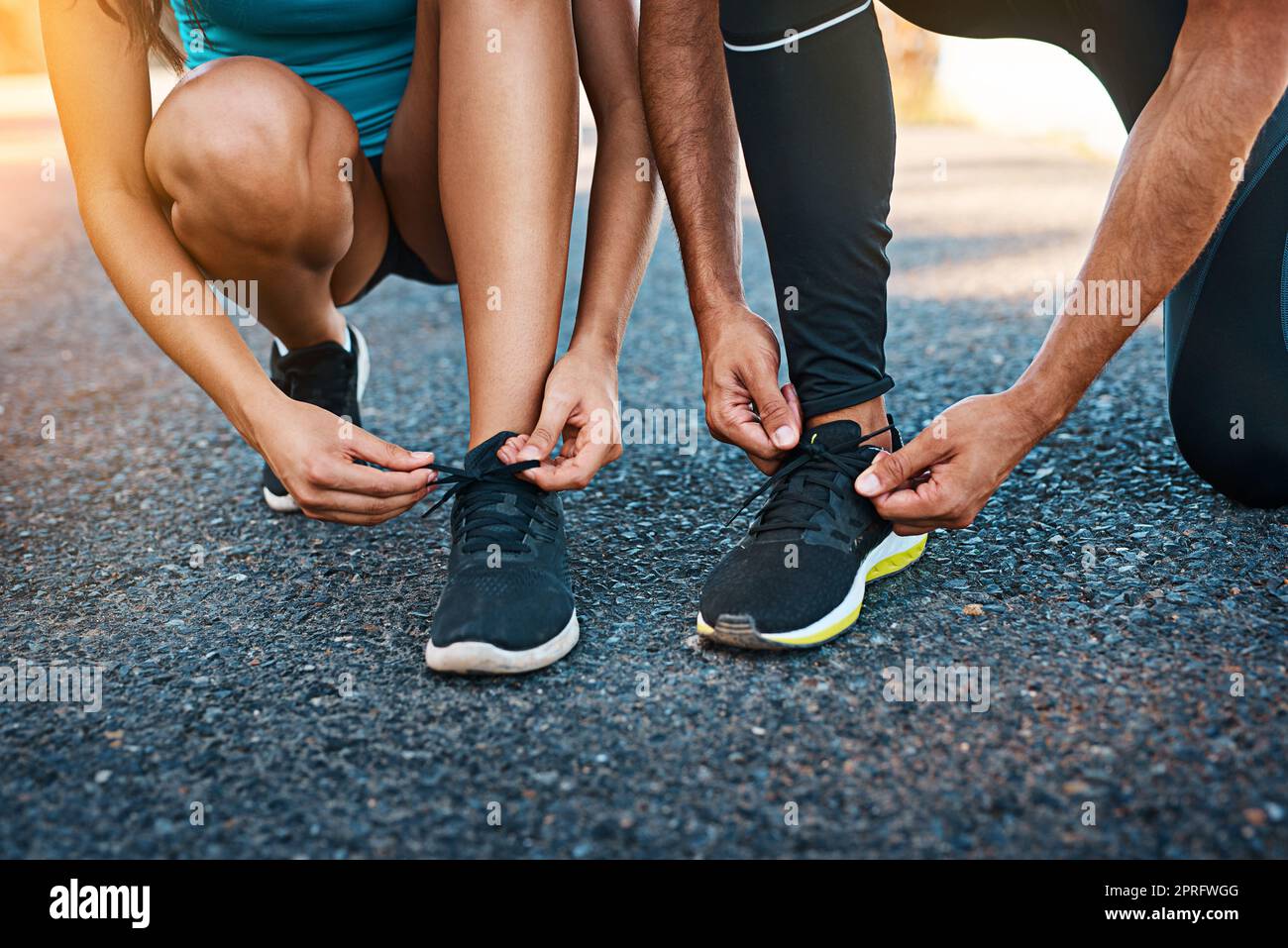 Allacciati e scendi in strada insieme. Una giovane coppia irriconoscibile che stringe le scarpe mentre sei fuori per una corsa. Foto Stock