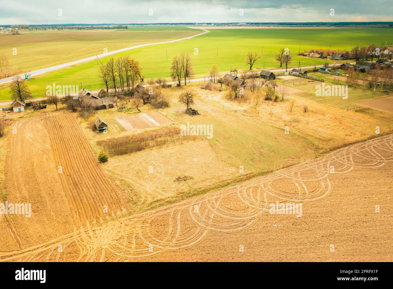 Bielorussia. Vista aerea del villaggio bielorusso. Splendido paesaggio rurale con vista dall'alto. Inizio della stagione primaverile agricola. Cingoli su terreni arati da macchinari agricoli Foto Stock