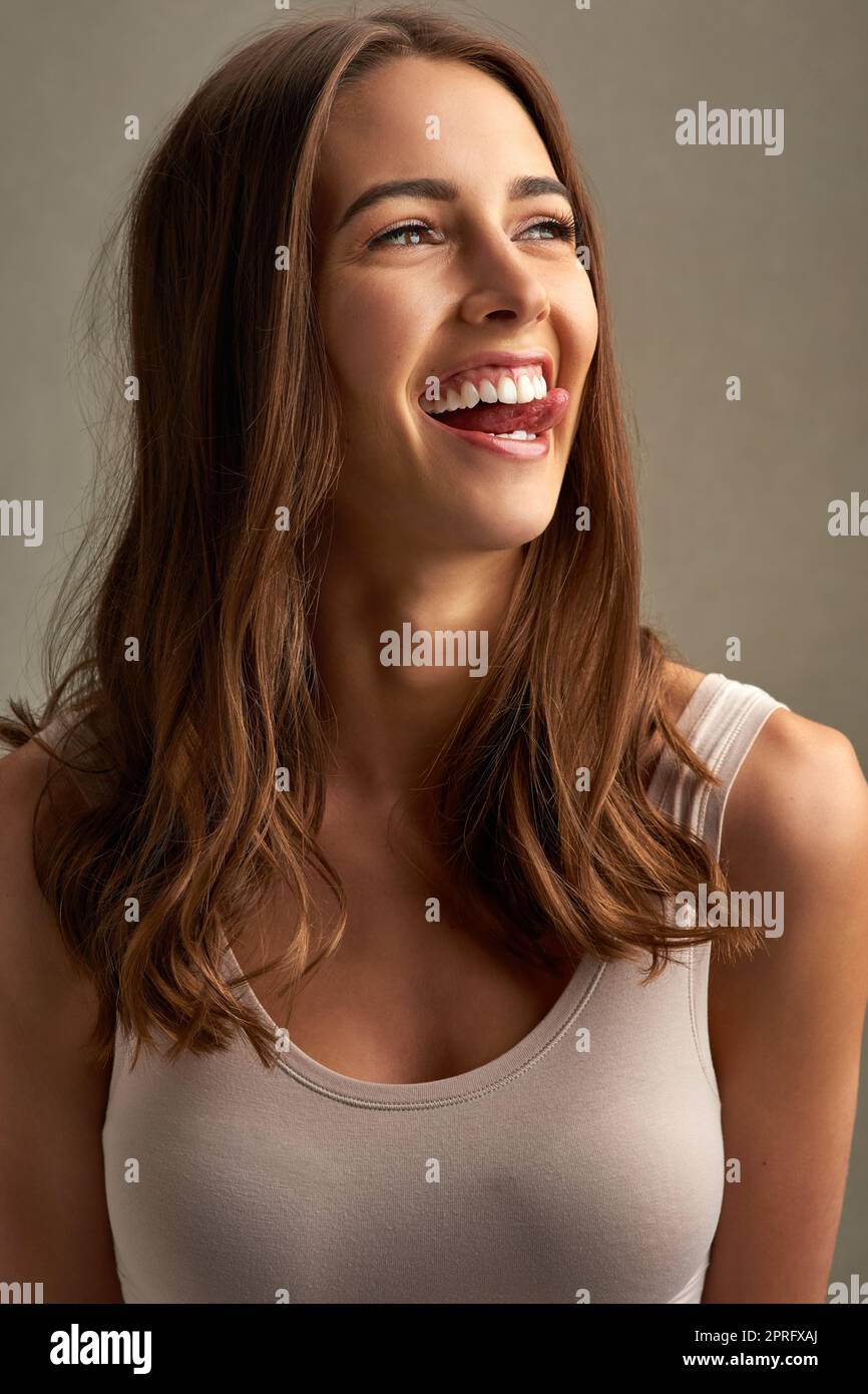 Mostrando il suo lato giocoso. Studio shot di una giovane donna attraente che fa un volto su uno sfondo marrone. Foto Stock