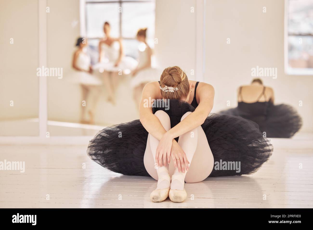 Balletto, depressione e ballerina triste dopo la pratica teatrale, le prove di danza o lo spettacolo in una sala da ballo o in uno studio. Stanco, prepotente e stress di ballerini professionisti seduti a piangere sul pavimento Foto Stock