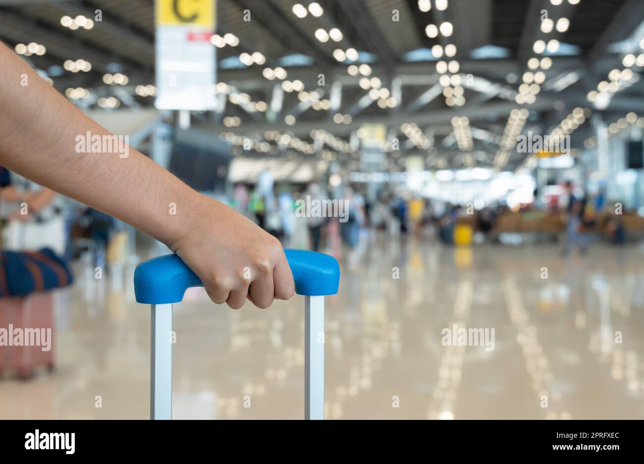 Donna con maniglia portabagagli con sfondo sfocato del terminal aeroportuale. Foto Stock