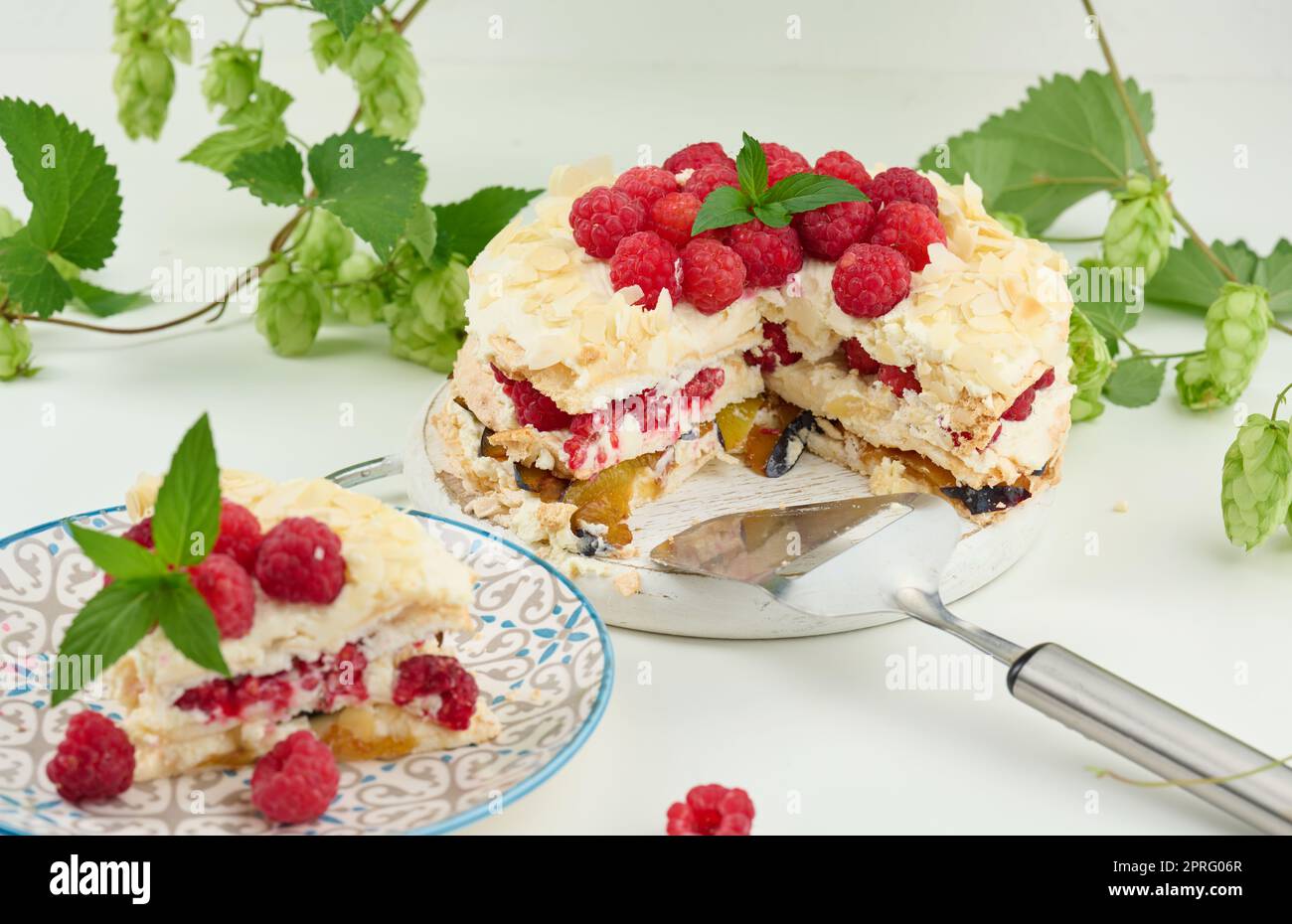 Torta di meringa rotonda con lamponi freschi su sfondo bianco, Pavlova dessert Foto Stock