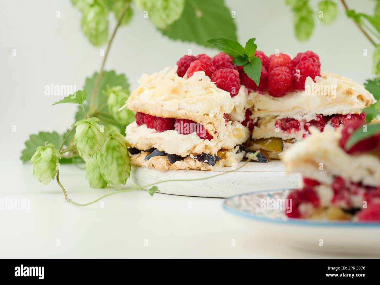 Torta di meringa rotonda con lamponi freschi su sfondo bianco, Pavlova dessert Foto Stock