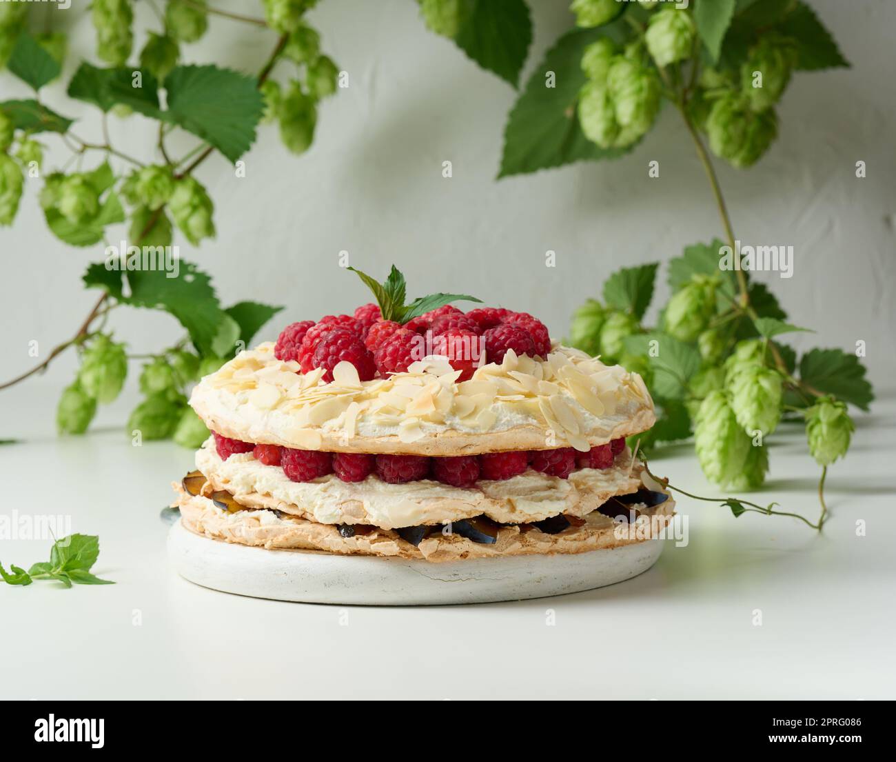 Torta di meringa rotonda con lamponi freschi su sfondo bianco, Pavlova dessert Foto Stock