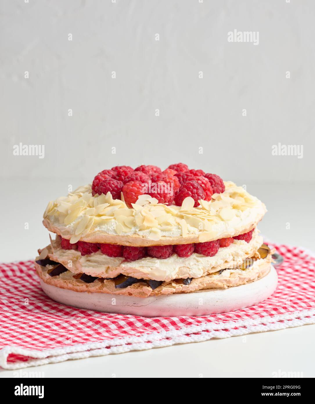 Torta di meringa rotonda con lamponi freschi su sfondo bianco, Pavlova dessert Foto Stock