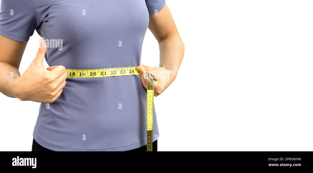 Primo piano le mani femminili negli abiti da ginnastica utilizzare un metro a nastro per misurare la vita. Nutrizione sana e concetto di perdita di peso. Ritratto su sfondo bianco con luce da studio. Foto Stock