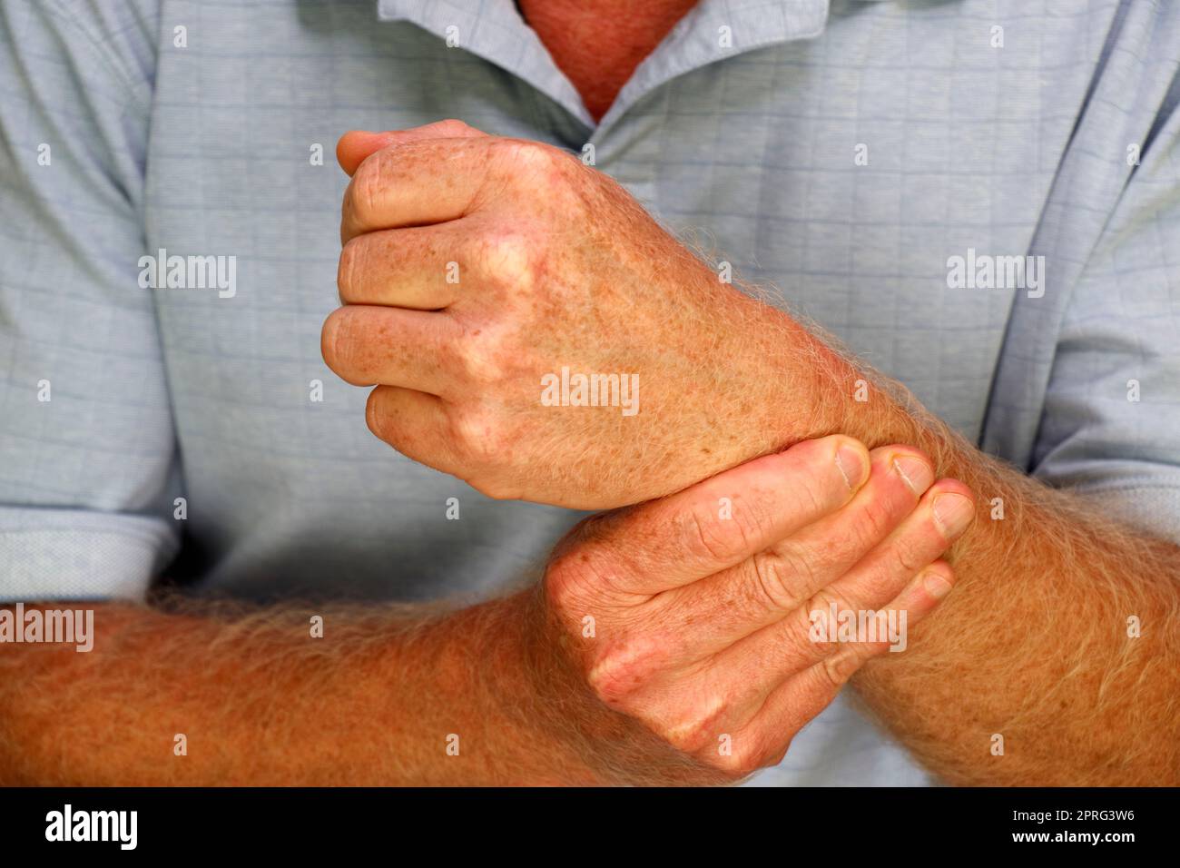 Dita della mano destra di un uomo maturo bianco che massaggia il polso sinistro Foto Stock