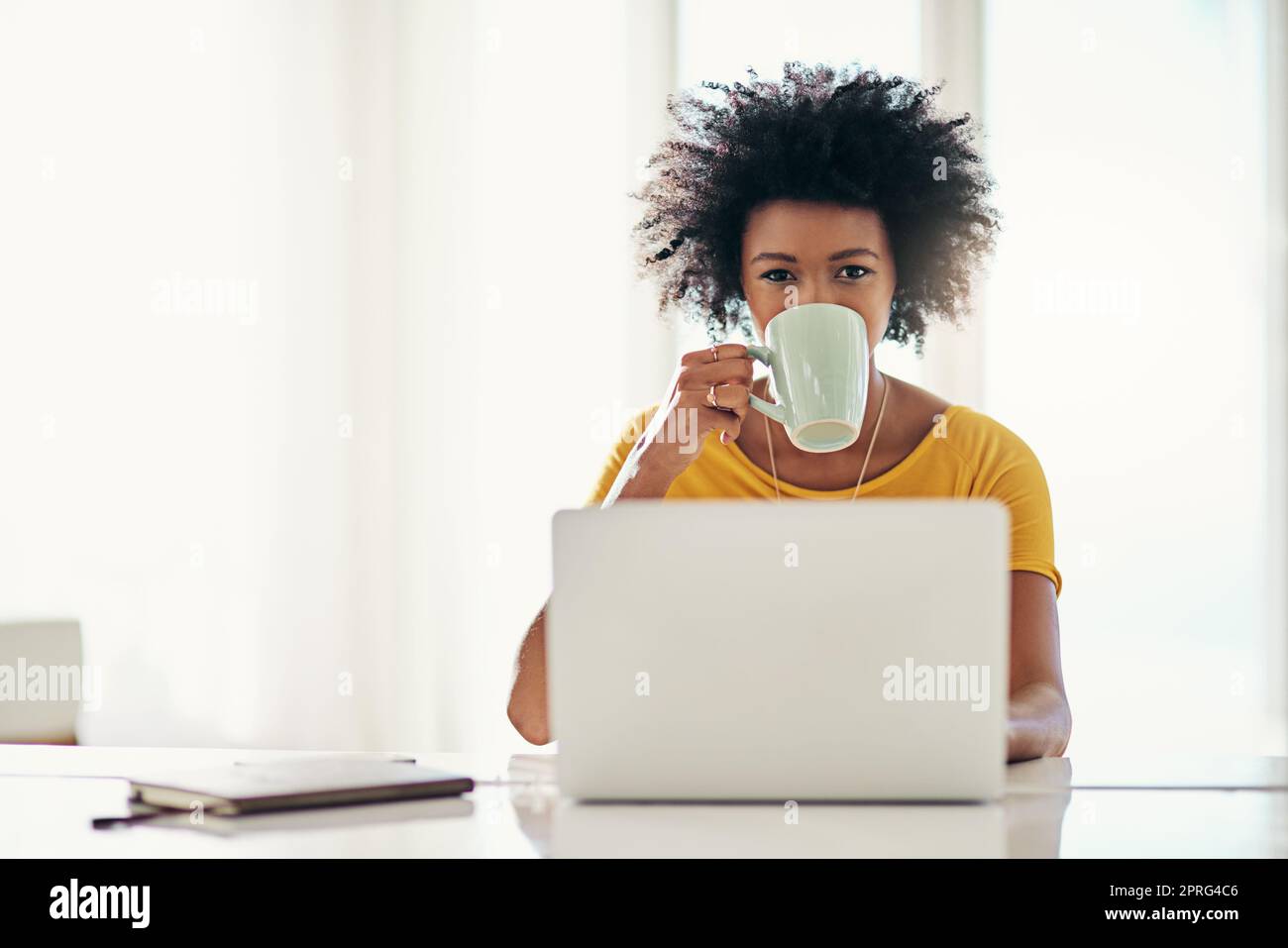 Il caffè mi fa andare avanti. Ritratto ritagliato di una giovane donna attraente che lavora sul suo notebook a casa. Foto Stock
