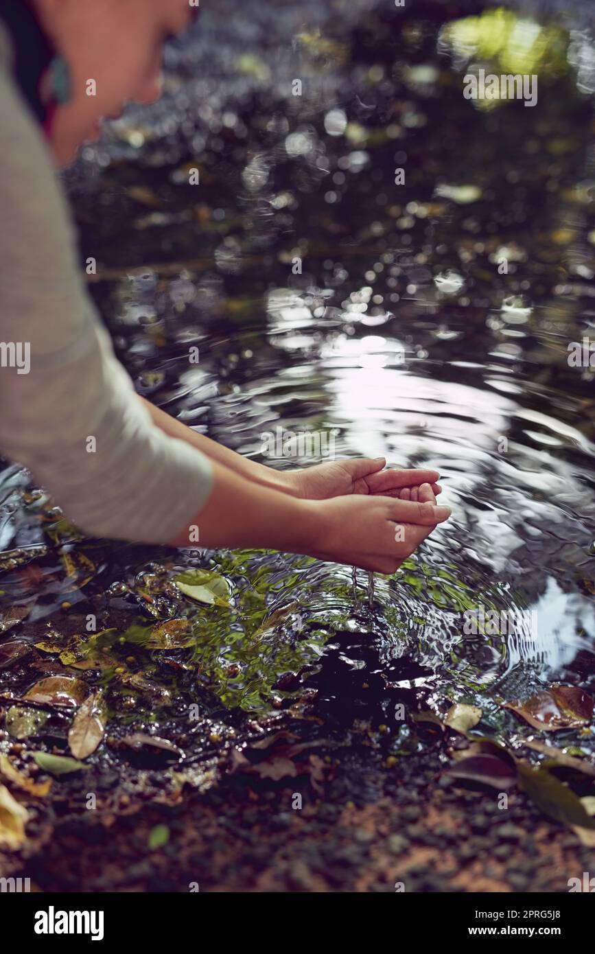 Acqua - con amore da Madre natura. Una donna che si lava le mani in uno stagno. Foto Stock