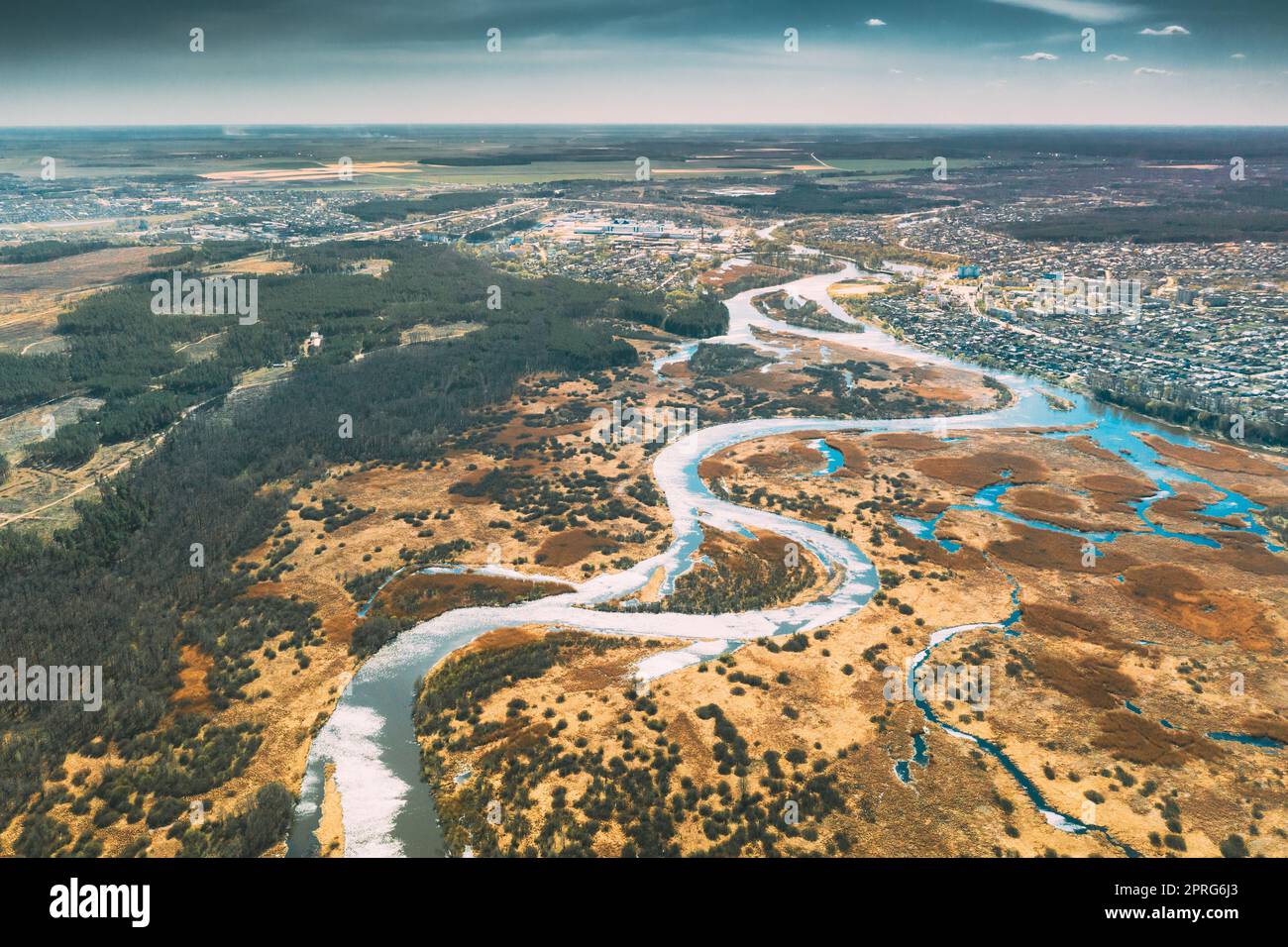 Bielorussia, Europa. Vista aerea fiume curvo e piccola città nel paesaggio primaverile. Curve fluviali curve e prati asciutti. Vista dall'alto della splendida natura europea da High Attitude. Vista droni. Bird's Eye View Foto Stock