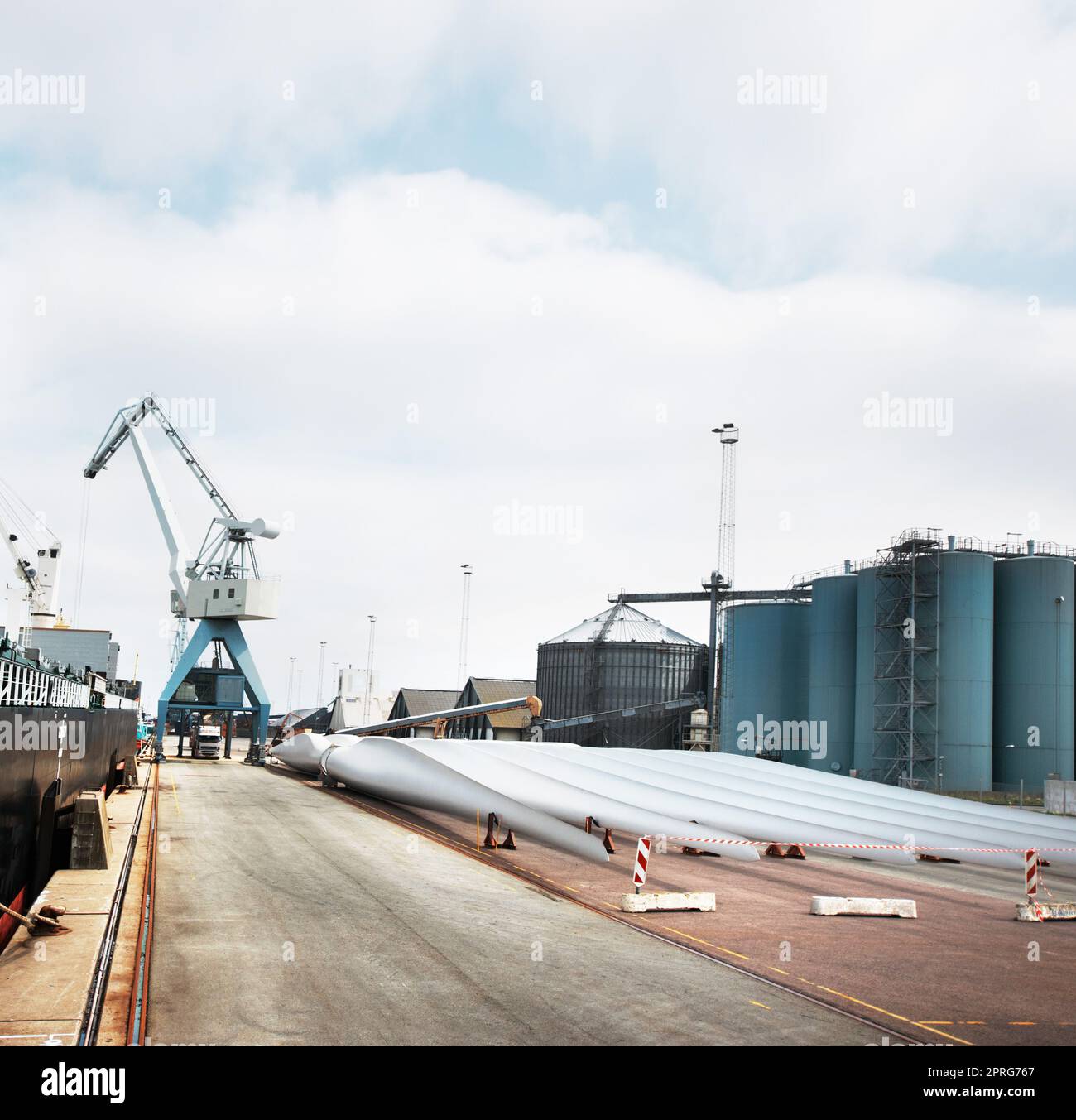 Logistica, spedizione e catena di approvvigionamento in un porto con una fabbrica, un magazzino o un impianto e una gru in background. Produzione, merci e merci per la consegna nell'industria dell'esportazione e dell'importazione Foto Stock