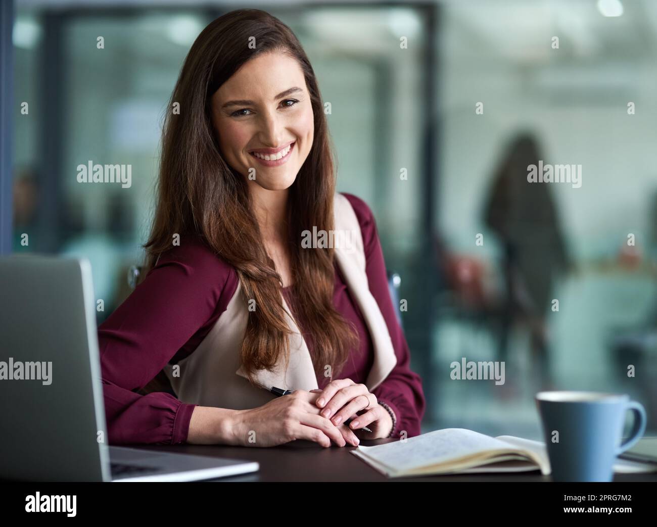Una donna d'affari seduta alla sua scrivania con il suo computer portatile. Foto Stock