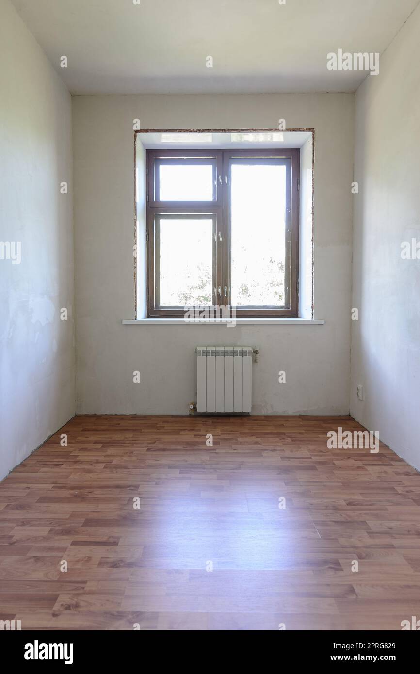 Vista della finestra in una piccola stanza dopo il rinnovo, il laminato effetto legno è posato sul pavimento Foto Stock
