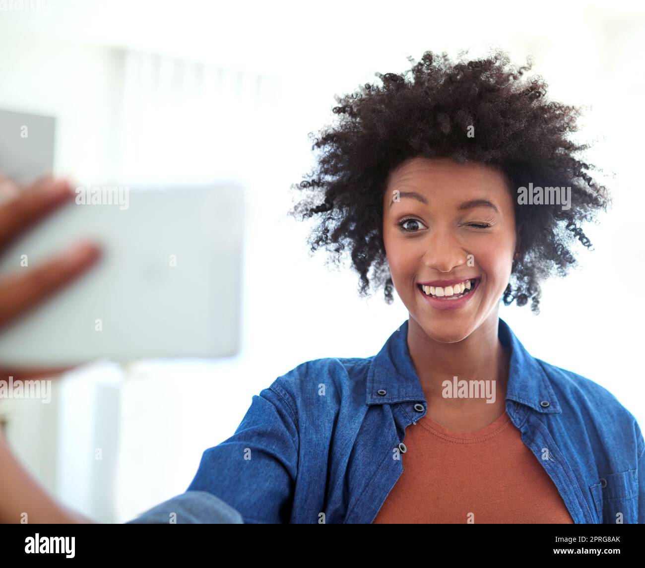 Sfruttare al massimo il suo tempo libero. Una giovane donna attraente che prende un selfie a casa. Foto Stock