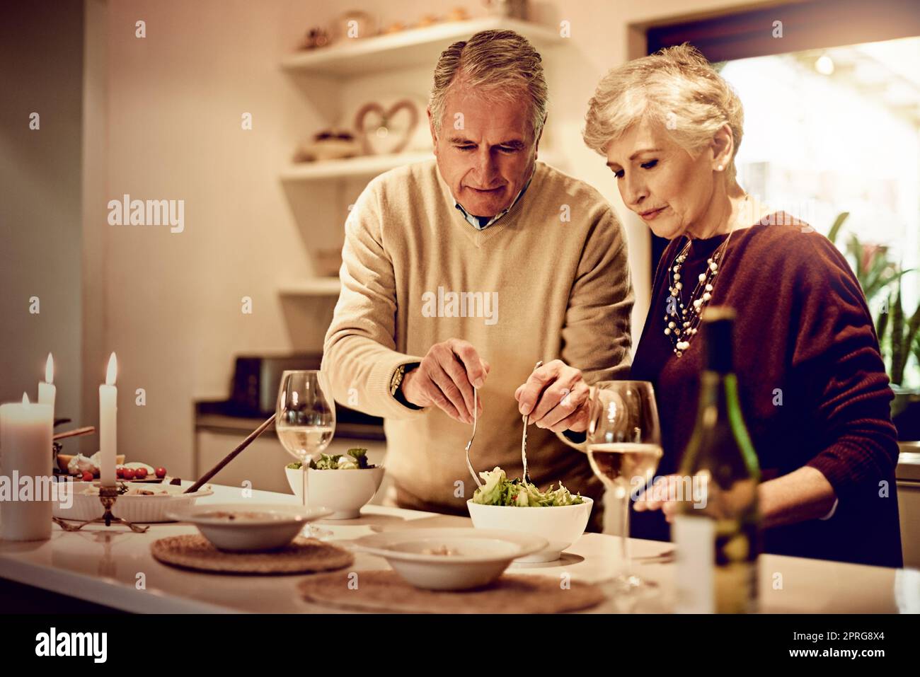 Qui, fate un po' di questa insalata, una coppia anziana che si prepara un pasto in cucina a casa. Foto Stock