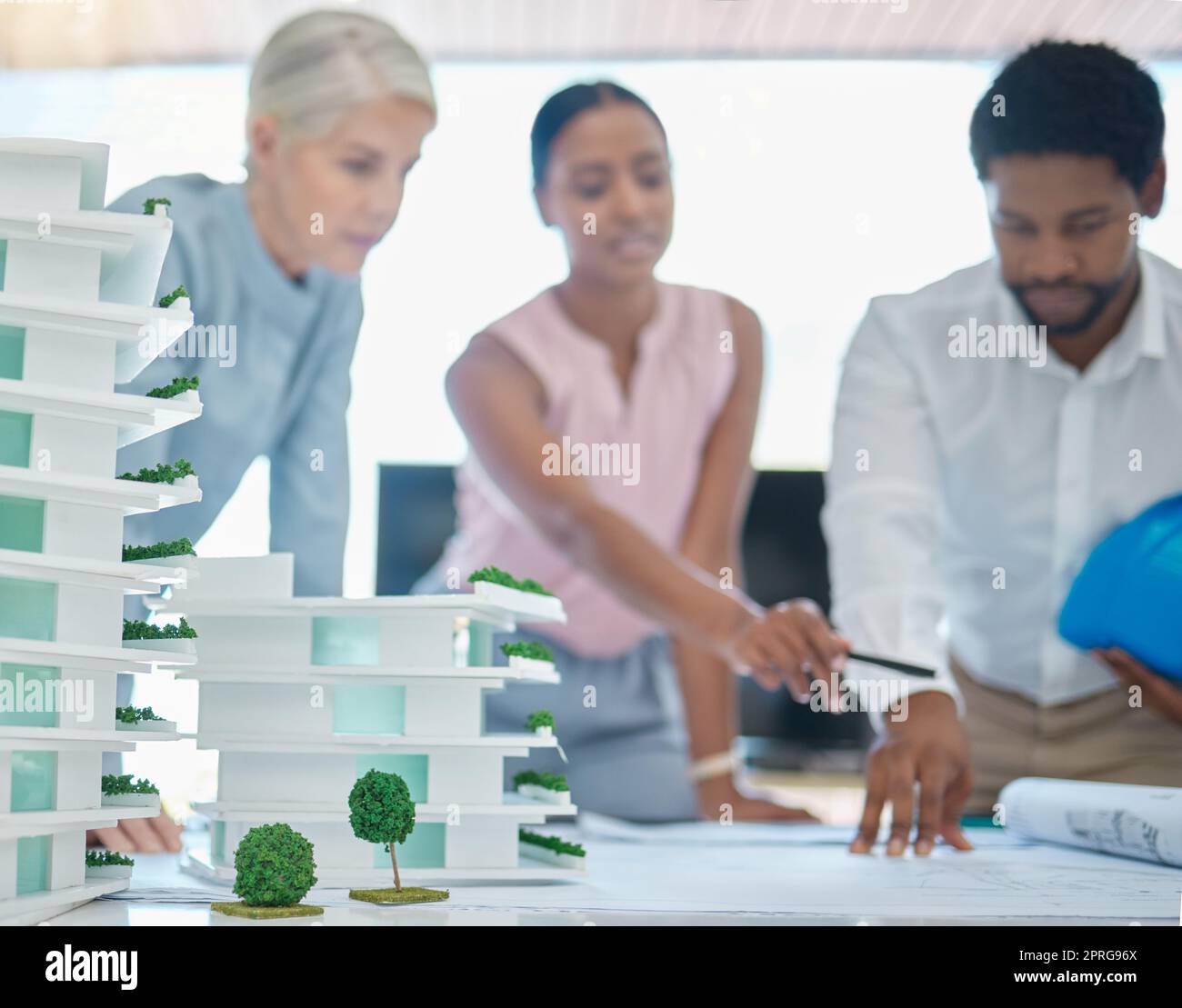 Architetto o ingegnere che progetta e progetta un edificio in una riunione in ufficio o in una sala riunioni. Pianificatore dello sviluppo urbano o gruppo di architettura con un modello 3d e lavorando su una strategia Foto Stock